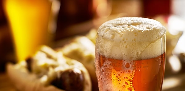 ipa and food pairing - IPA beer with overflowing foamy head in mug served with bratwursts